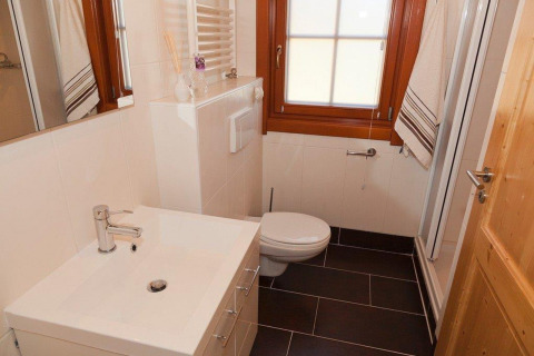 Moderne badkamer met witte wastafel, toilet, spiegel en raam in Boekhorst Royal + Sauna in Brunssummerheide, Nederland.