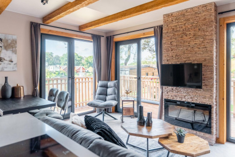 Sala moderna en tiny house Heidelodge en Brunssummerheide, Países Bajos, con ventanas grandes y balcón.