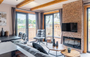 Modernes Wohnzimmer im Tiny House Heidelodge in Brunssummerheide, Niederlande, mit großen Fenstern.