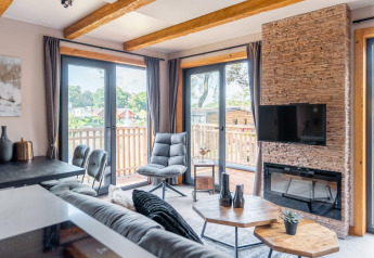 Soggiorno moderno nella tiny house Heidelodge a Brunssummerheide, Paesi Bassi, con grandi finestre e balcone.