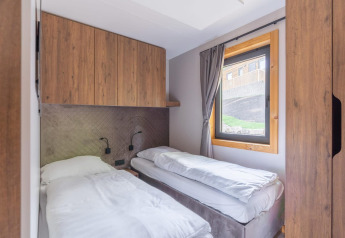 Camera da letto nella tiny house Heidelodge, Brunssummerheide, Paesi Bassi, con due letti singoli e armadi in legno.