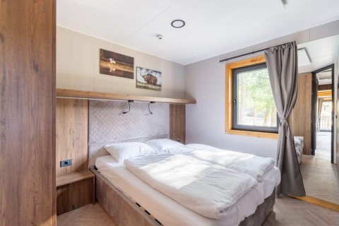 Chambre lumineuse du tiny house Heidelodge à Brunssummerheide, Pays-Bas, avec lit double et grande fenêtre.