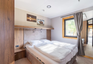 Chambre lumineuse du tiny house Heidelodge à Brunssummerheide, Pays-Bas, avec lit double et grande fenêtre.