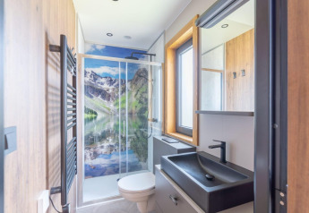 Baño moderno en minicasa de Heidelodge en Brunssummerheide, Países Bajos, con mural de montaña en la ducha.