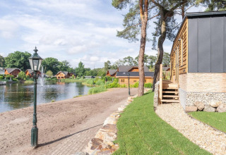 Vista del lago y cabañas de madera en Heidelodge, Brunssummerheide, Países Bajos, con naturaleza verde.