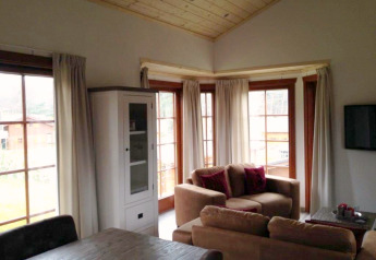 Woonkamer in lodge Boekhorst bij Brunssummerheide, Nederland, met grote ramen, banken en houten plafond.