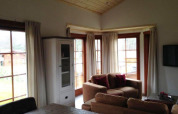 Wohnzimmer der Lodge Boekhorst bei Brunssummerheide, Niederlande, mit Sofas, Holzdecke und Fenstern.