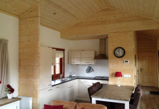 Vue intérieure d'un lodge en bois chaleureux avec cuisine moderne et salle à manger à Boekhorst, Brunssummerheide.