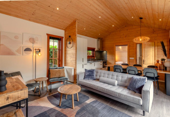 Moderne Lodge-Wohnzimmer mit Holzdecke, grauem Sofa, Essbereich und Küche in Boekhorst, Brunssummerheide.