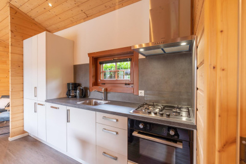 Cocina moderna en la cabaña Boekhorst en Brunssummerheide, Países Bajos, con estufa de gas y paredes de madera.