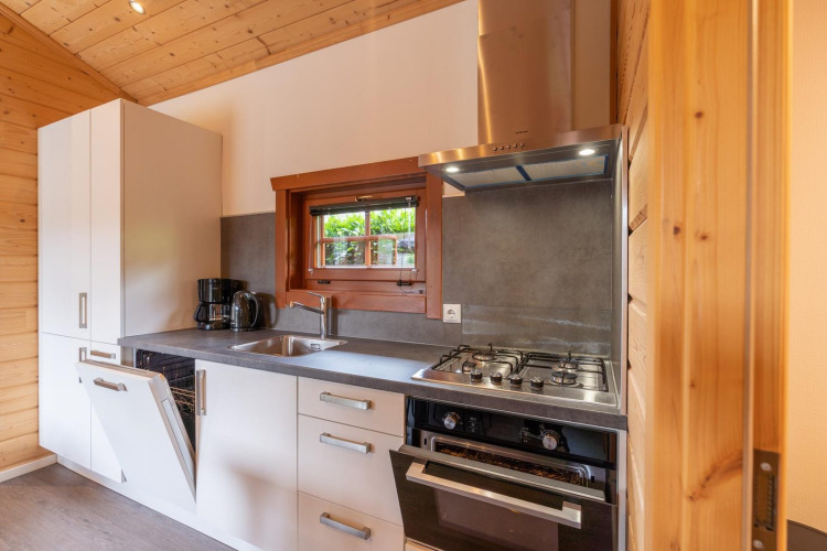 Cocina moderna de una cabaña en Boekhorst, Brunssummerheide, Países Bajos, con estufa y lavavajillas abierto.