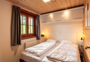 Schlafzimmer mit zwei Einzelbetten, Holzdecke, Fenster und Schränken in Boekhorst Lodge, Brunssummerheide, Niederlande.