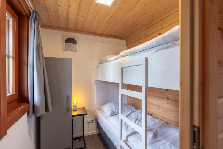 Habitación luminosa con literas y techo de madera en Boekhorst Lodge, Brunssummerheide, Países Bajos.