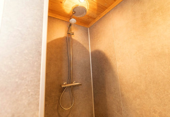 Moderne Dusche in der Boekhorst-Lodge bei Brunssummerheide, Niederlande, mit Holzdecke und Fliesen.