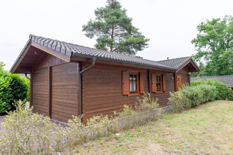 Vue extérieure du lodge Boekhorst Royal avec façade en bois, arbustes verts et pelouse en pleine journée.