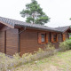 Udvendig udsigt af Boekhorst Royal lodge med træfacade, grønne buske og græsplæne, dagtimer.