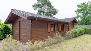 Vue extérieure du lodge Boekhorst Royal avec façade en bois, arbustes verts et pelouse en pleine journée.