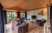 Stue i Boekhorst Royal lodge ved Brunssummerheide, Holland, med træloft, sofagruppe og store vinduer.
