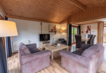 Woonkamer van Boekhorst Royal lodge bij Brunssummerheide, Nederland, met houten plafond en zithoek.