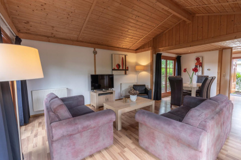 Sala de estar en Boekhorst Royal lodge en Brunssummerheide, Países Bajos, con techo de madera y sofá cómodo.