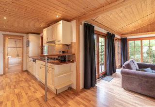 Acogedora cabaña Boekhorst Royal con interiores de madera, cocina y ventanales en Brunssummerheide, Países Bajos.