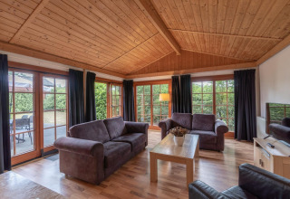 Soggiorno al Boekhorst Royal lodge a Brunssummerheide, Paesi Bassi, con soffitto in legno e ampie finestre.