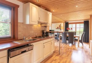 Cucina accogliente e zona pranzo in un lodge Boekhorst Royal, Brunssummerheide, Paesi Bassi, con legno.