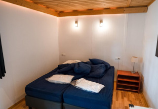Dormitorio con cama doble, sábanas azules, techo de madera y lámparas en Boekhorst Royal, Brunssummerheide.