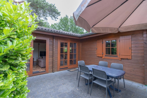 Buitenterras bij Boekhorst Royal lodge, Brunssummerheide, Nederland, met tafel, stoelen en parasol.
