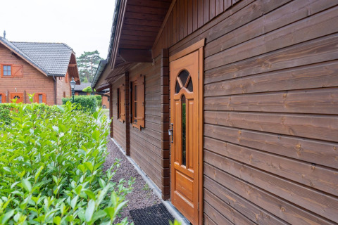 Vista exterior del Boekhorst Royal lodge en Brunssummerheide, Países Bajos, con fachada de madera y arbustos.