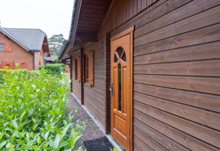 Vista exterior del Boekhorst Royal lodge en Brunssummerheide, Países Bajos, con fachada de madera y arbustos.