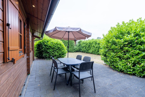 Terrasse extérieure du lodge Boekhorst Royal à Brunssummerheide, Pays-Bas, avec table, chaises et parasol.