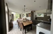 Modernes L-Pavilion-Lodge bei Brunssummerheide, Niederlande, mit offener Küche, Essbereich und Wohnzimmer.