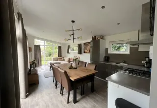 Moderne lodge L-Pavilion ved Brunssummerheide i Holland med åbent køkken, spisebord og hyggelig stue.