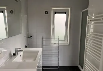 Modernes Badezimmer im L-Pavilion, Brunssummerheide, Niederlande, mit Waschbecken und Fenster.