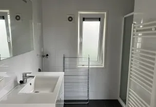 Moderne badkamer in L-Pavilion, Brunssummerheide, Nederland, met grote wastafel en raam.