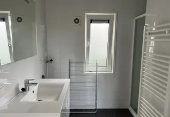 Moderne badeværelse på L-Pavilion, Brunssummerheide, Holland, med vask, brusekabine og vindue.