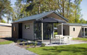 Modernes Tiny House bei Reestervallei in den Niederlanden mit Terrasse, Gartenmöbeln und Sonnenschirm.