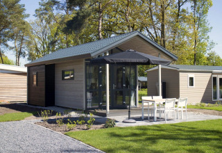 Modern tiny house at Reestervallei in the Netherlands, with terrace, garden furniture, and sun umbrella.