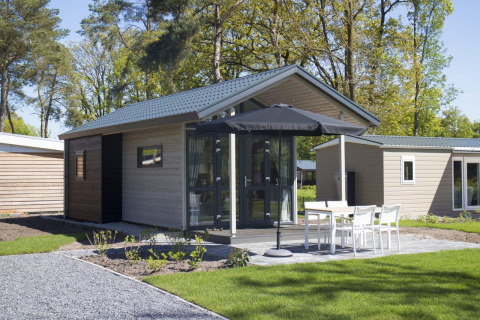 Moderne tiny house bij Reestervallei in Nederland, met terras, tuinmeubilair en een zwarte parasol.