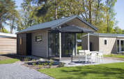 Modern tiny house at Reestervallei in the Netherlands, with terrace, garden furniture, and sun umbrella.