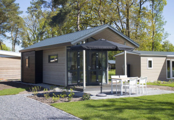 Tiny house moderna a Reestervallei nei Paesi Bassi, con terrazza, mobili da giardino e ombrellone nero.