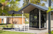 Modernes Tiny House bei Reestervallei in den Niederlanden mit Terrasse, Sitzgruppe und Sonnenschirm.