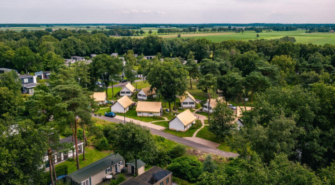 Luftaufnahme von Glampingtent im Reestervallei, Niederlande, mit Lodges zwischen Bäumen und grünen Feldern.