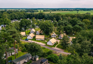 Luftaufnahme von Glampingtent im Reestervallei, Niederlande, mit Lodges zwischen Bäumen und grünen Feldern.