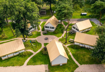 Aerial view of Glampingtent lodges at Reestervallei in the Netherlands, surrounded by green trees.