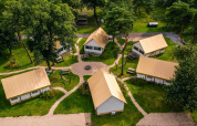 Luftfoto af Glampingtent-lodges på Reestervallei i Holland, omgivet af grønne træer og stier.