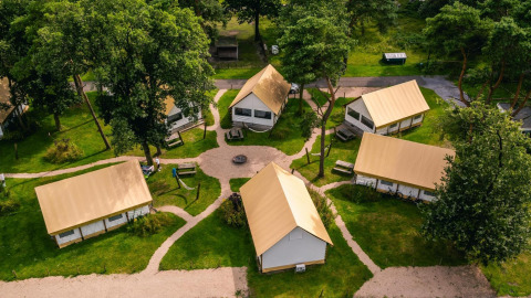 Luftfoto af Glampingtent-lodges på Reestervallei i Holland, omgivet af grønne træer og stier.