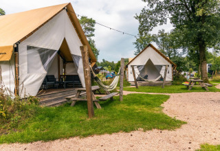 Glamping tent at Reestervallei in the Netherlands, with deck, hammock, picnic tables and green lawn.