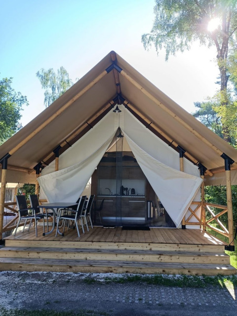 Glamping tent at Reestervallei, Netherlands, featuring a wooden deck, outdoor seating, and canvas walls.